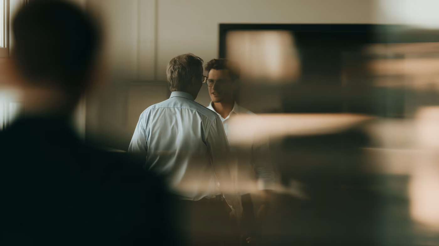 Two men in conversation, the foreground out of focus.