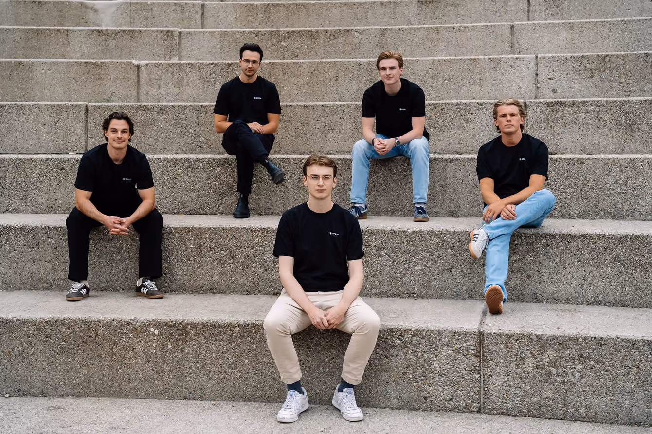 Five people sitting on wide concrete steps, looking at the camera.