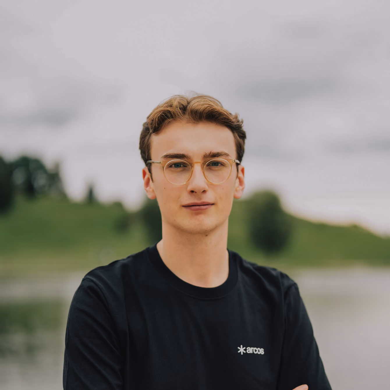 Louis Wübben in glasses, arms folded, in front of a lake.