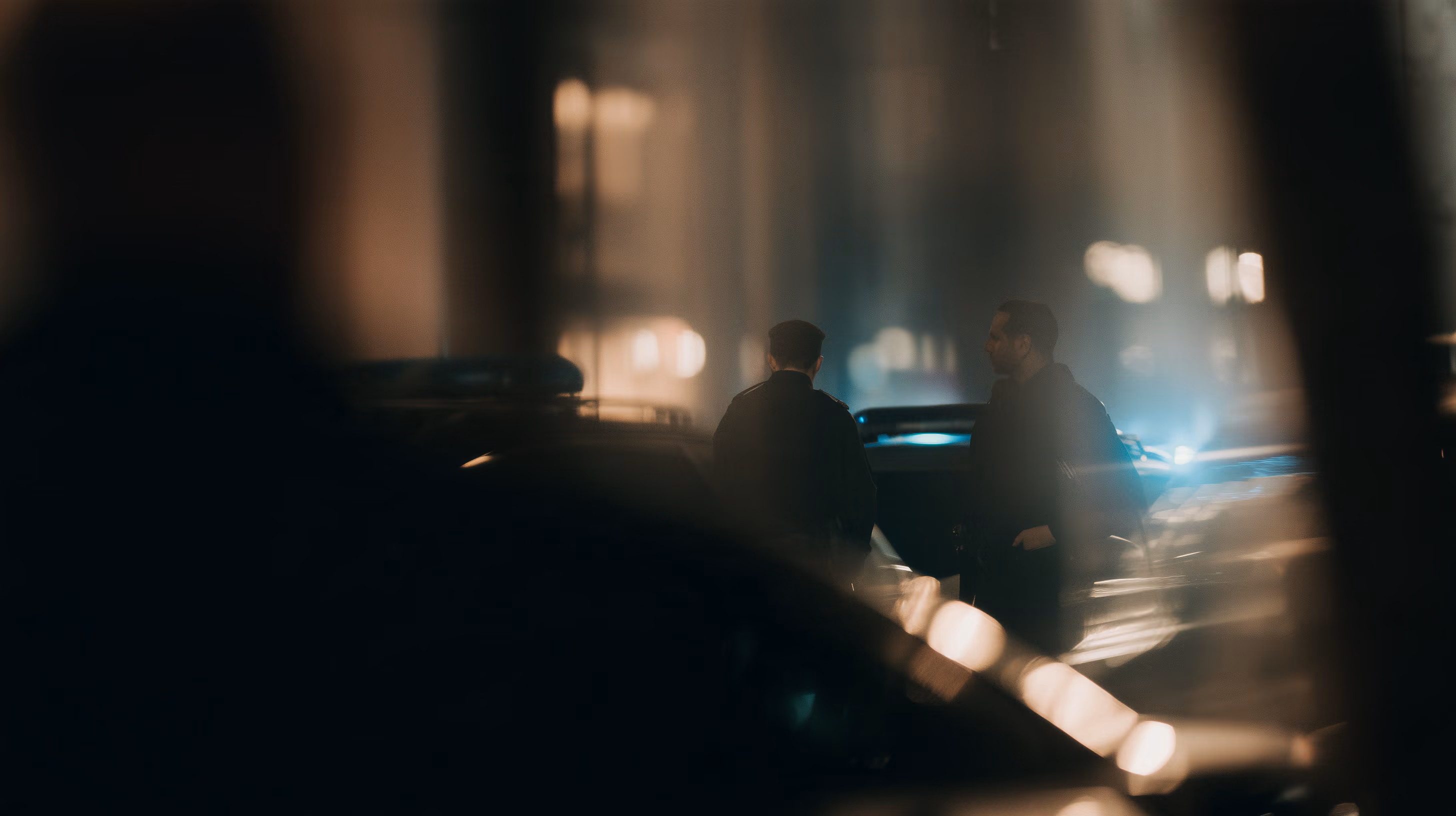 A street at night, a blue emergency light in the distance.