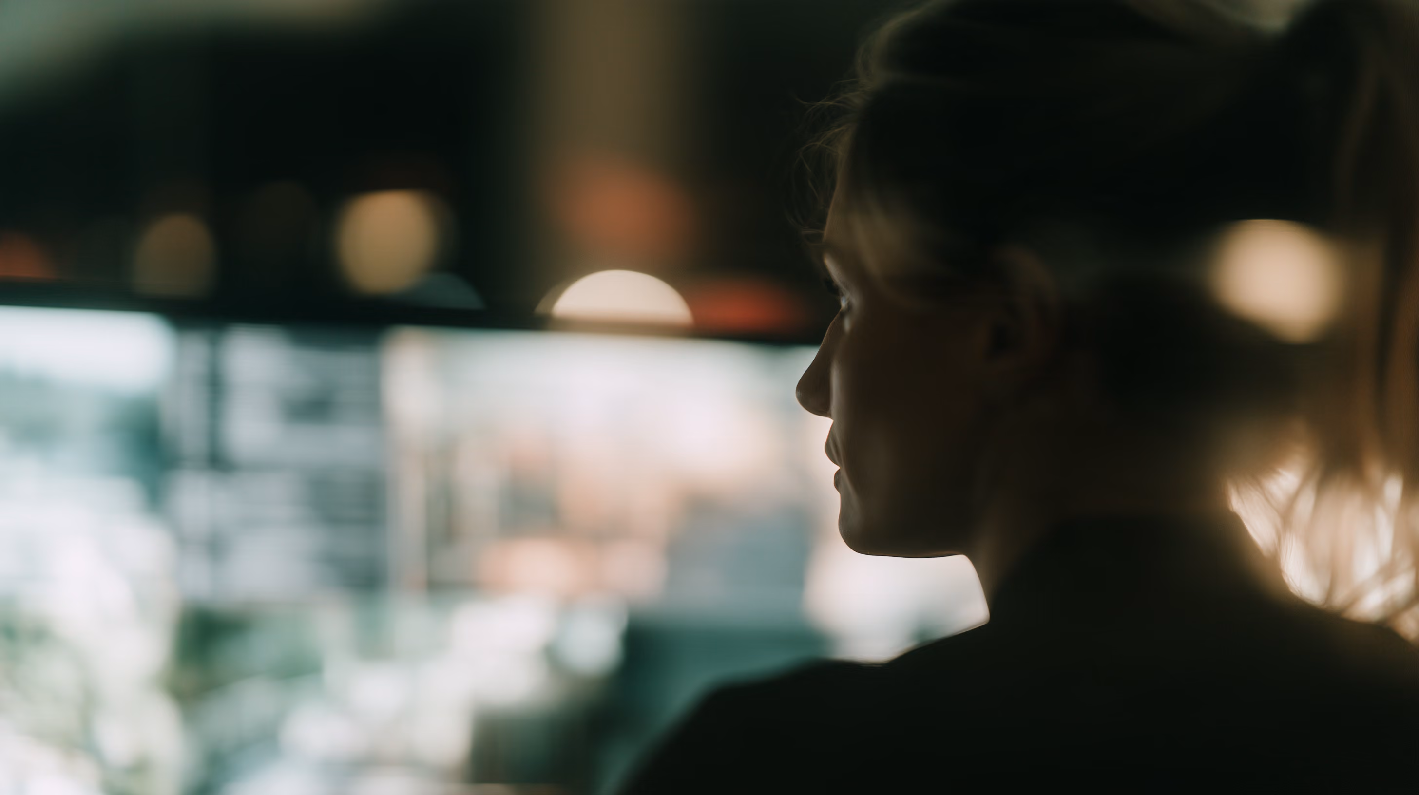 A person in profile, lit by the glow of several screens.