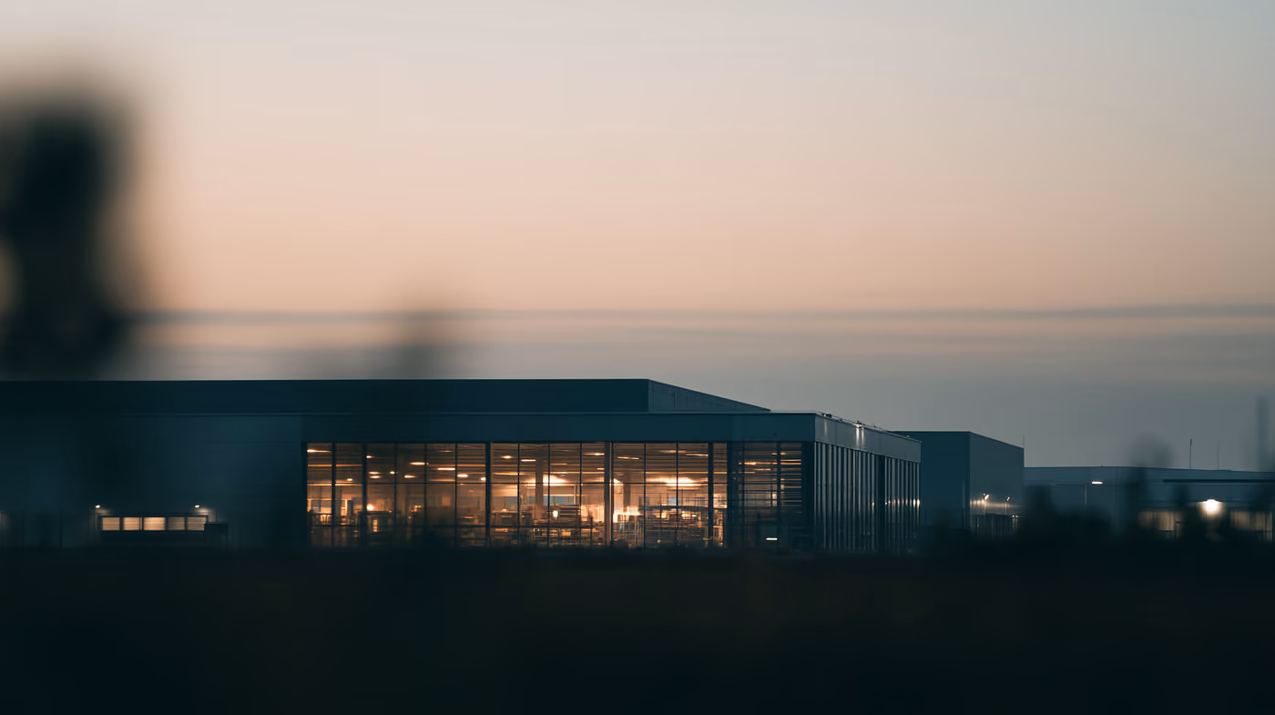 A low commercial building at dusk with its windows lit.