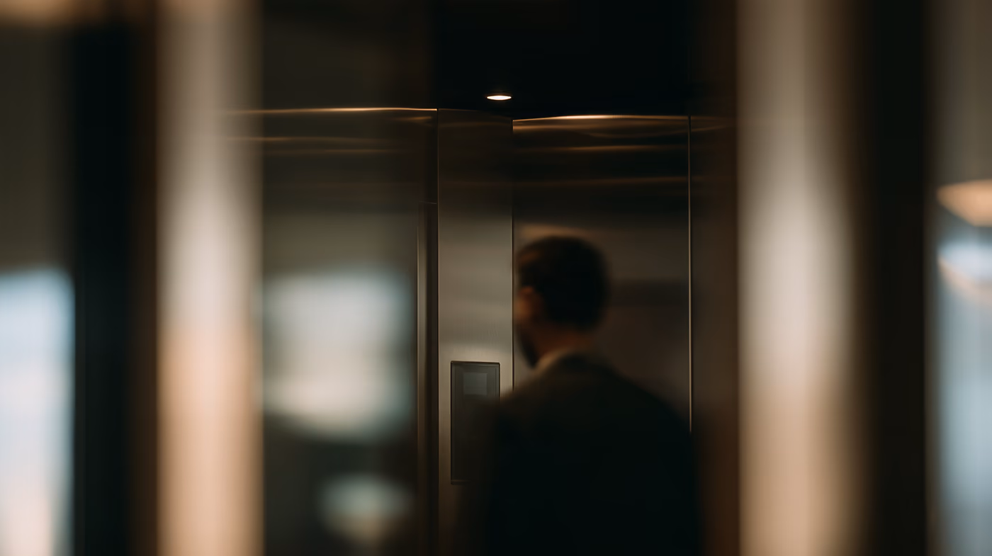 A man beside a lift door, the foreground out of focus.