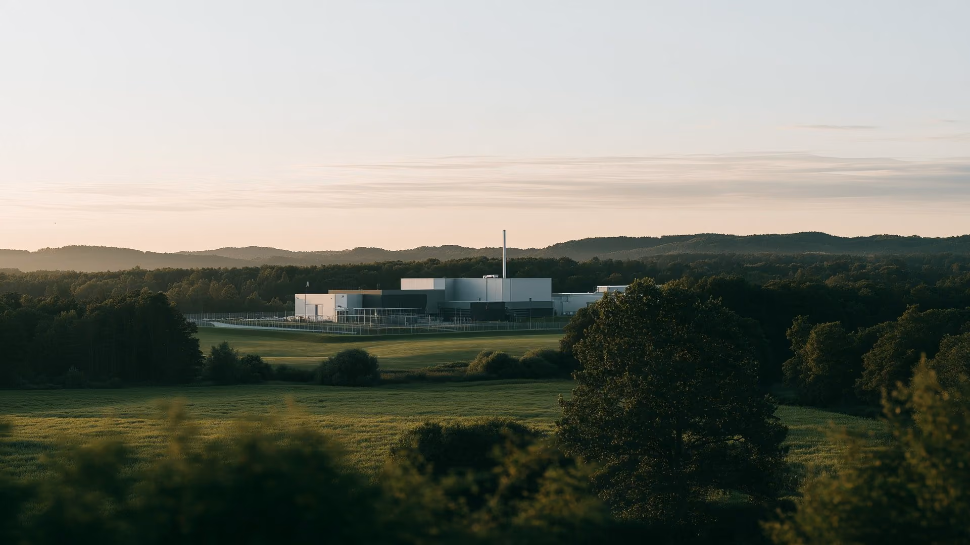Industrial site with a perimeter fence in open countryside at dusk, site security and video monitoring
