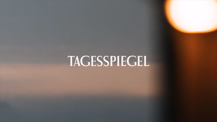The Tagesspiegel wordmark over a blurred photograph of a hazy sky at dusk, a warm light out of focus on the right.
